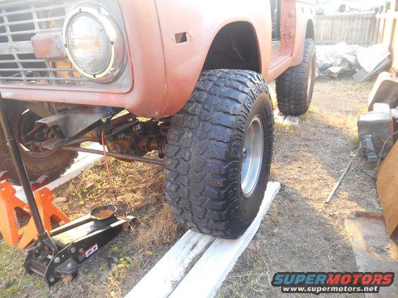 Front of a 1972 Ford Bronco on jack stands, showing the grille, headlight, and large off-road tires
