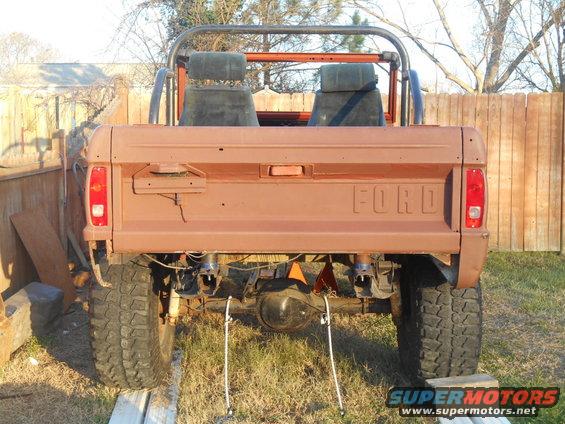 Brown 1978 Ford Bronco rear view, showing tailgate with FORD lettering, aftermarket roll cage, and large tires