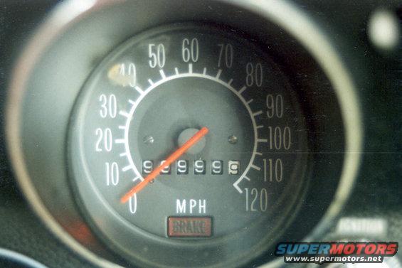 Speedometer gauge with needle pointing to 0, showing 999999 miles, and a BRAKE indicator light
