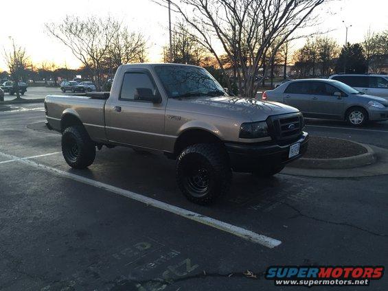 Tan Ford Ranger pickup truck with lifted suspension and large tires parked in a lot