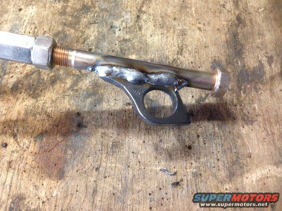 Custom metal bracket welded onto a rod with nuts and bolts. It has a circular opening