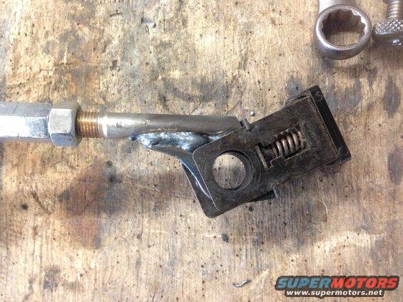 Welded metal linkage with nuts and a spring-loaded mechanism