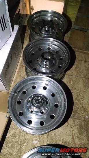 Three aluminum wheels with five lug nuts and a center cap with a Ford logo