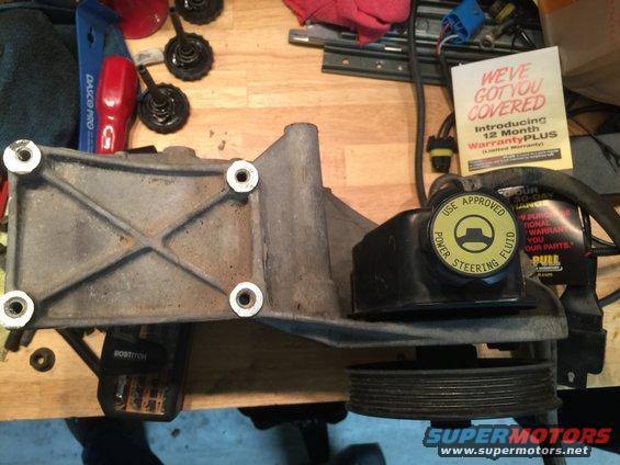 Power steering pump and bracket assembly with pulley. Yellow cap reads 'USE APPROVED POWER STEERING FLUID'