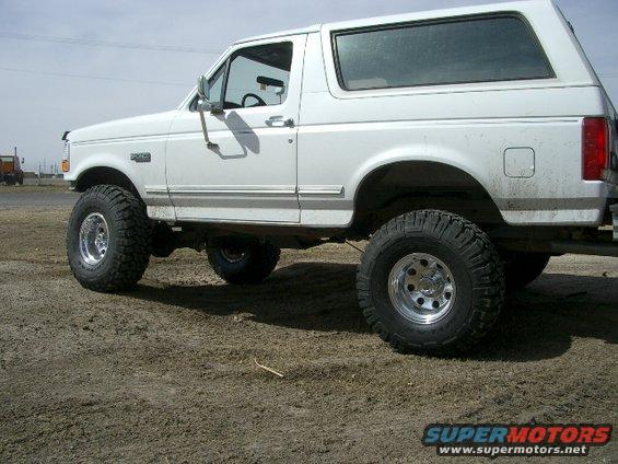 White Ford Bronco SUV with lifted suspension and large tires, viewed from the side