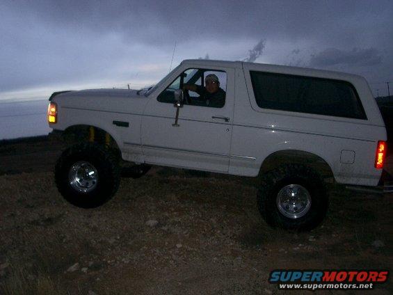 White SUV with a driver, lifted suspension, off-road tires, side view
