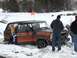 1979 Ford Bronco - Ford Bronco with orange stripe stuck in snow, people are trying to get it out.