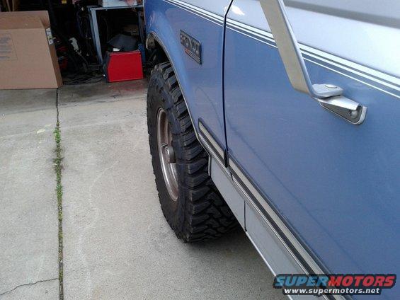 Side view of a blue 1996 Ford Bronco showing its large tires and chrome trim