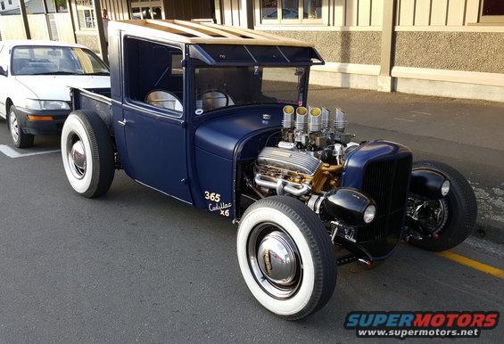 Blue hot rod pickup truck, exposed engine, whitewall tires, text '365 Cadillac x6'