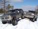 1979 Ford Bronco - Two Ford Broncos navigate a snowy terrain, one with a lifted suspension and aggressive tires.