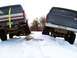 1979 Ford Bronco - Two 1979 Ford Broncos are shown off-roading in a snowy environment, with one vehicle's rear end angled upwards on a rock.
