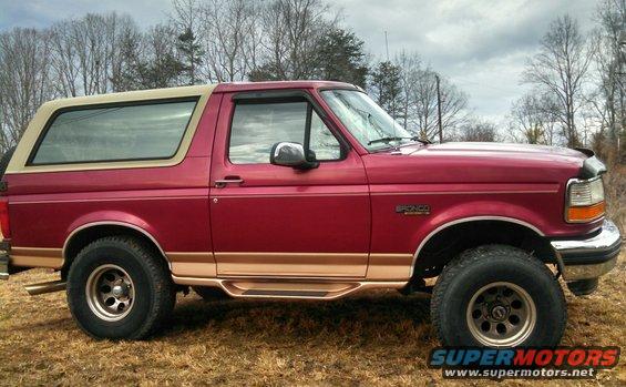 Red 1995 Ford Bronco with tan removable top, lifted with 33-inch tires