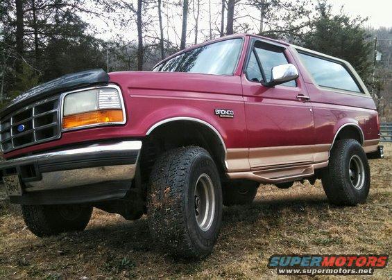 Red Ford Bronco with a lift kit and large tires parked outside