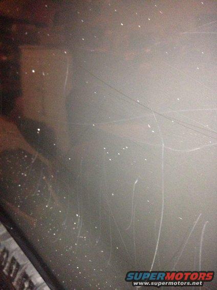 Close-up of gray car paint with numerous scratches and dust specks