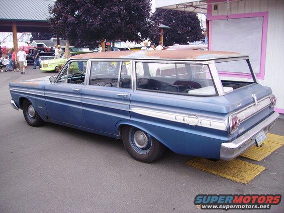 Blue station wagon with chrome trim and rusty roof, seen from the rear