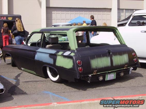 Station wagon with primer paint, whitewall tires, and custom rear bumper. License plate reads '4PJT25'