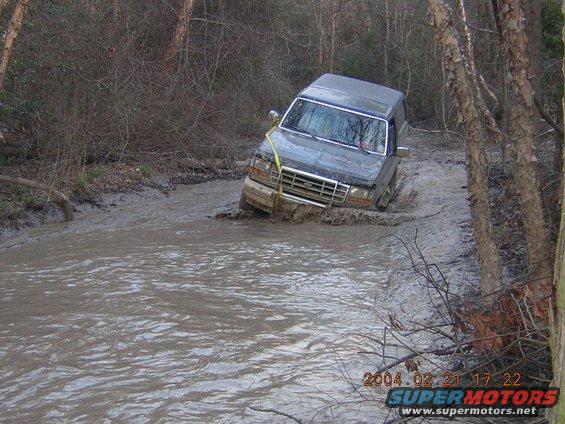 Dark SUV stuck in muddy stream, 1992 Ford Bronco