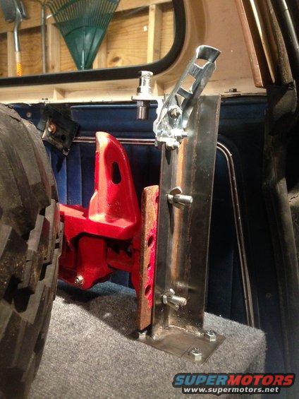 Custom metal bracket bolted to a storage box, next to a large tire inside a vehicle