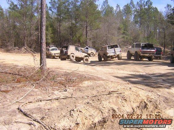 Several off-road vehicles parked on a dirt track in a wooded area. Date stamp reads 2004.02.22