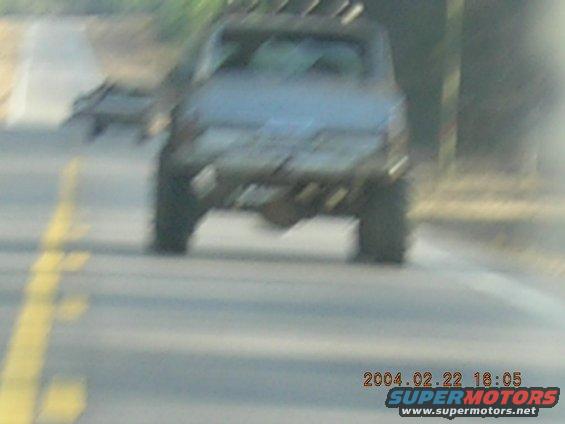 Rear view of a dusty 1984 Chevrolet Blazer driving on a road