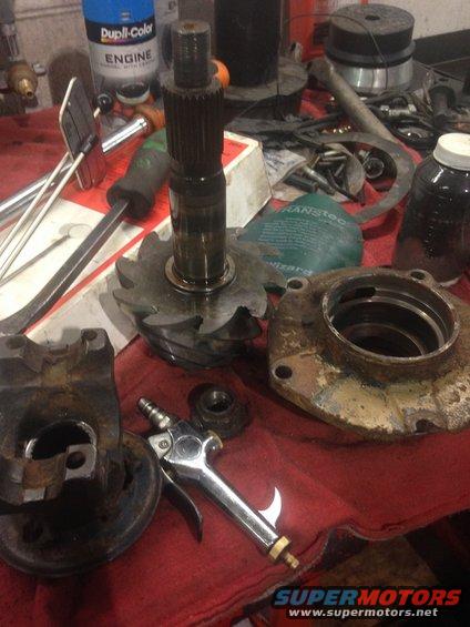Differential gears and housing parts laid out on a red cloth with tools and a can of engine paint