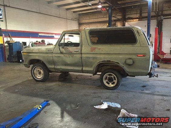 1978 Ford Bronco in a garage, side view. It has some rust and is in need of repair