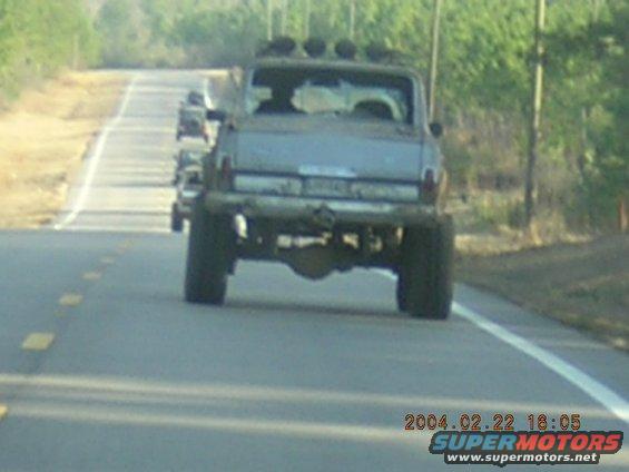 Modified pickup truck with roof lights driving on a road, another vehicle behind it