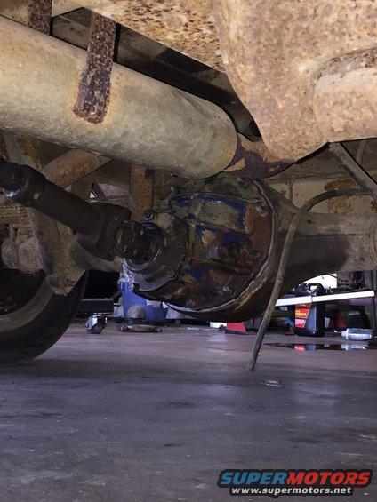 Underside view of a vehicle's rear axle and differential assembly with exhaust pipe