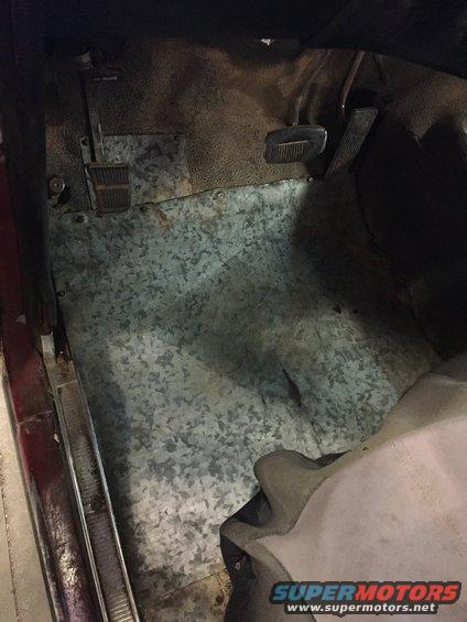 vehicle interior floor with metal sheeting and pedals visible