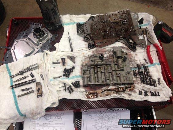 Disassembled automatic transmission valve body and components laid out on towels on a red cart