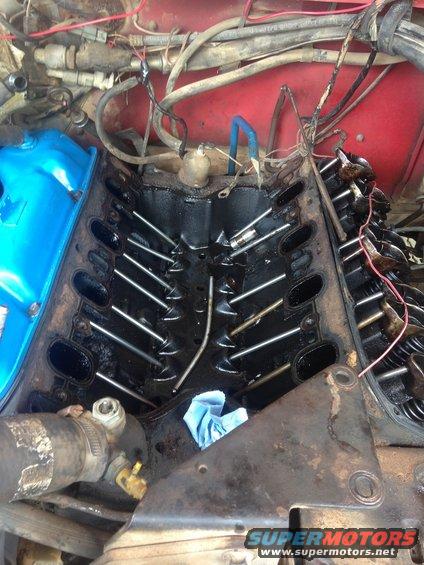 Engine bay with intake manifold removed, showing pushrods and valve train