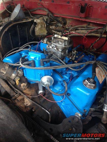Close-up of a blue-painted engine with a carburetor and distributor cap