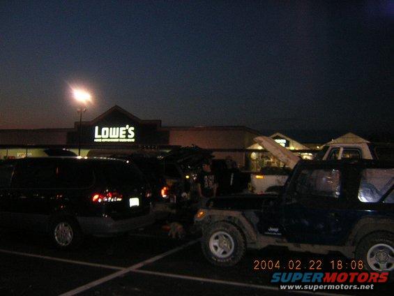 Jeep Wrangler parked in front of a Lowe's store at dusk, with other vehicles nearby