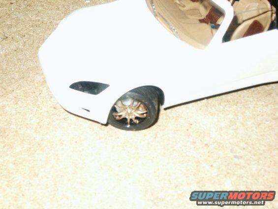 Close-up of a white model car's front wheel and fender