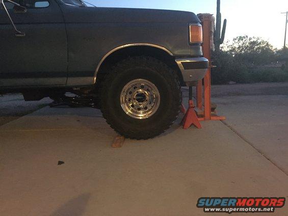 1991 Ford Bronco side view, dark color, large tires on jack stands