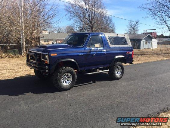 Blue Ford Bronco with aftermarket hood scoop and bull bar, lifted suspension, and soft top