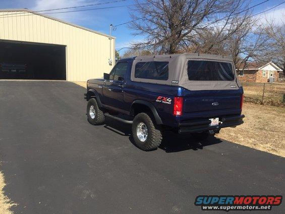Blue Ford Bronco with soft top parked on asphalt driveway
