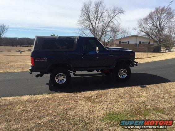 Dark blue Ford Bronco with a soft top, lifted suspension, and off-road tires, seen from the 3/4 front angle