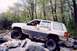 1978 Ford Bronco - A silver SUV is shown off-roading over a pile of large rocks.