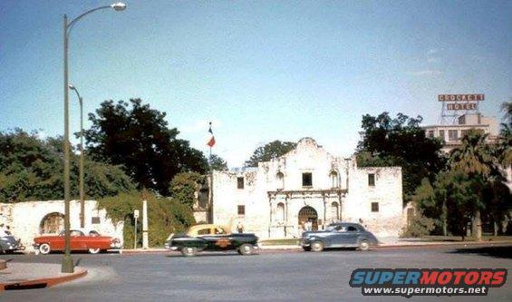 Vintage cars on street in front of the Alamo; Crockett Hotel sign visible
