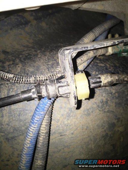 Close-up of a plastic bracket holding fuel lines and wiring harness, with blue and black corrugated tubing