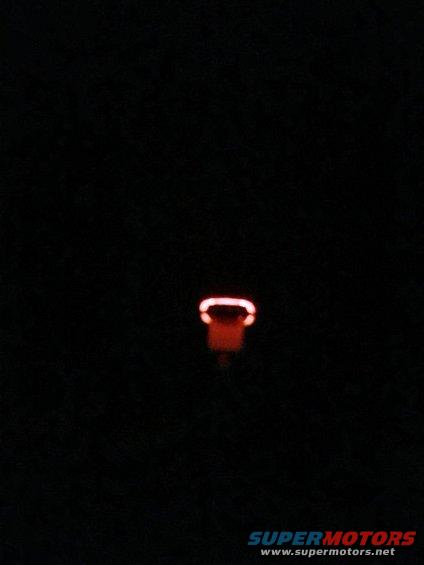 Red indicator light glowing in darkness, with 'SUPERMOTORS' text at bottom right
