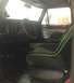1979 Ford Bronco - The interior of a 1979 Ford Bronco features custom racing seats with green trim and a wooden steering wheel.