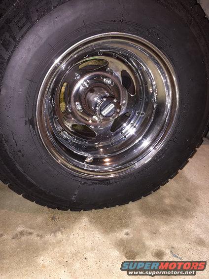 Chrome wheel with a black tire. The center cap has 'WARN' written on it