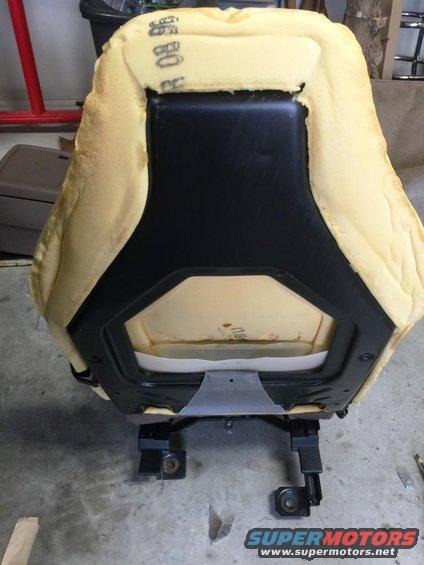 Bottom view of car seat foam and black plastic frame with metal seat rails attached