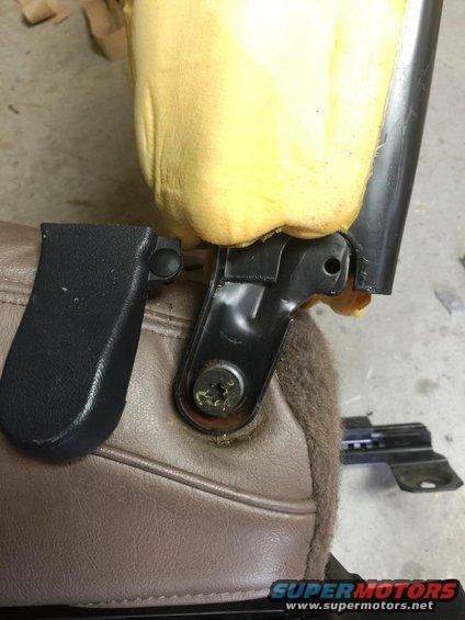 Car seat bracket with exposed yellow foam and brown upholstery