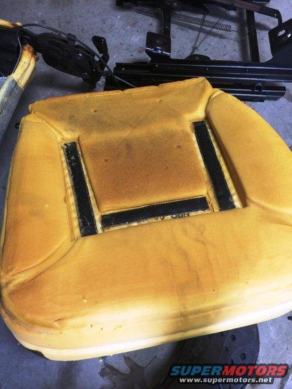 Car seat cushion with exposed foam and metal seat frame parts in the background
