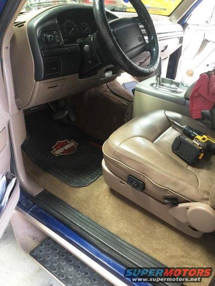 Tan leather driver's seat and dashboard of a 1996 Ford Bronco, with a drill on the seat