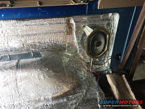Car interior with silver soundproofing material covering the floor and door panel, and a speaker mounted on the door