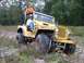 1978 Ford Bronco - Yellow Jeep CJ-5 navigating rough terrain with two occupants.